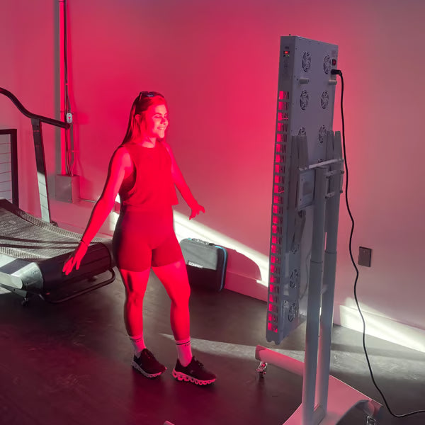 A woman using the Vital Red Light therapy device at her local gym for post workout muscle recovery|workout muscle soreness|Red Light Therapy for Muscle