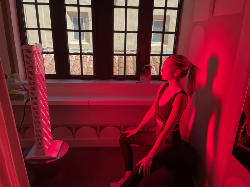 Red Light Therapy for Rosacea|A woman with a ponytail does a yoga backbend on the floor, illuminated by red light, suggesting Light Therapy for Rosacea Relief, with a white chair and window in the background.
