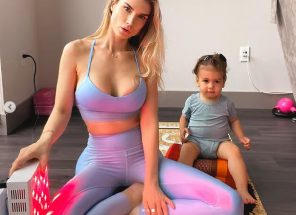 A mother using her Vital Pro red light therapy device to reduce the appearance of stretch marks