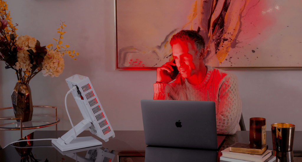 Guy using red light therapy while he works
